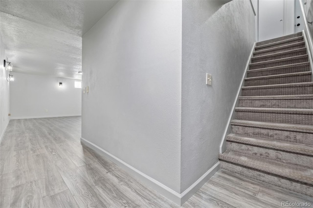 stairs with a textured ceiling and hardwood / wood-style flooring