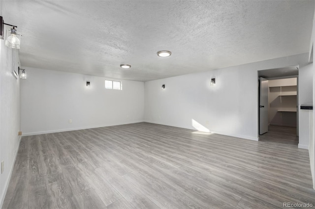 spare room featuring a textured ceiling and light hardwood / wood-style flooring