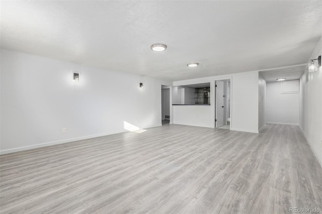 unfurnished living room with a textured ceiling and light hardwood / wood-style flooring