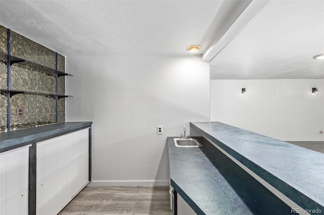 bar featuring sink, a textured ceiling, and hardwood / wood-style flooring