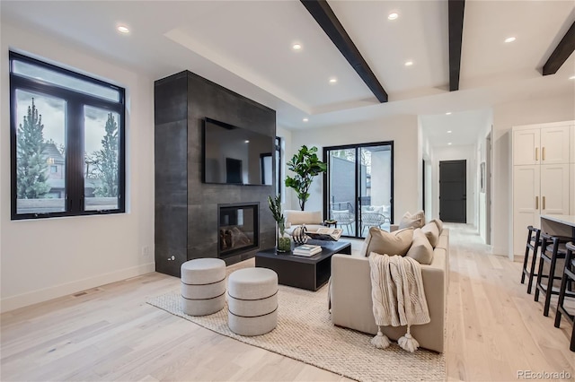 living room with a large fireplace, beam ceiling, and light wood-type flooring