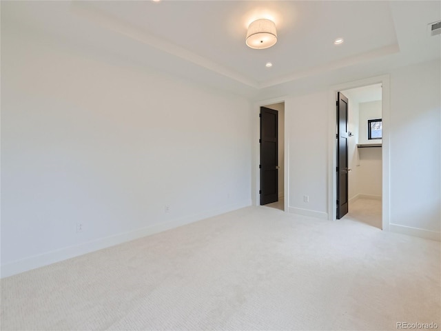 unfurnished bedroom with light carpet and a tray ceiling