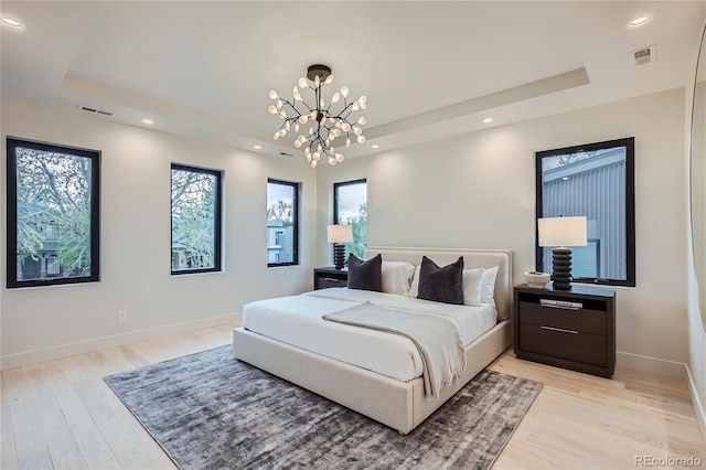 bedroom with an inviting chandelier, a raised ceiling, and multiple windows