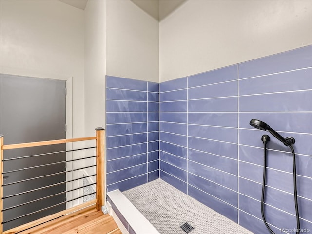 bathroom with a tile shower and hardwood / wood-style flooring