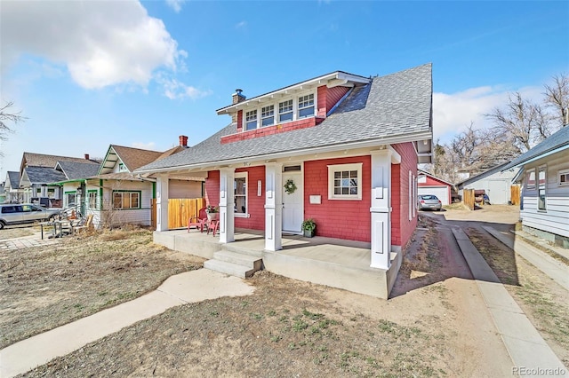 bungalow-style home with a chimney, a porch, driveway, and a shingled roof