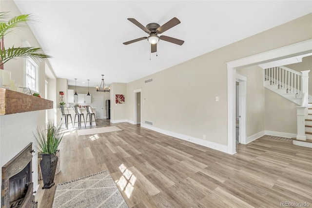 unfurnished living room with stairway, visible vents, light wood-type flooring, and baseboards