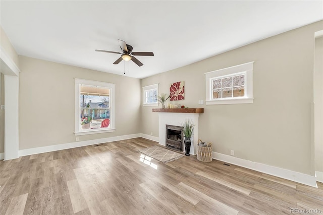 unfurnished living room with a fireplace with flush hearth, a ceiling fan, baseboards, and wood finished floors