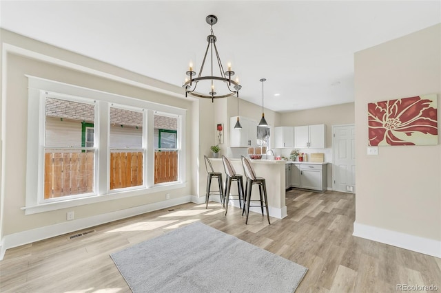 kitchen featuring a kitchen breakfast bar, plenty of natural light, visible vents, and light wood finished floors