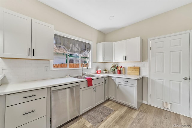 kitchen with dishwasher, light wood-style floors, tasteful backsplash, and a sink