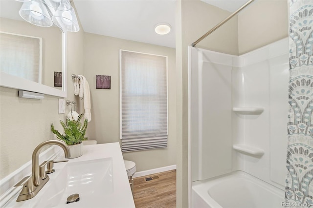 bathroom featuring visible vents, toilet, a sink, shower / washtub combination, and wood finished floors