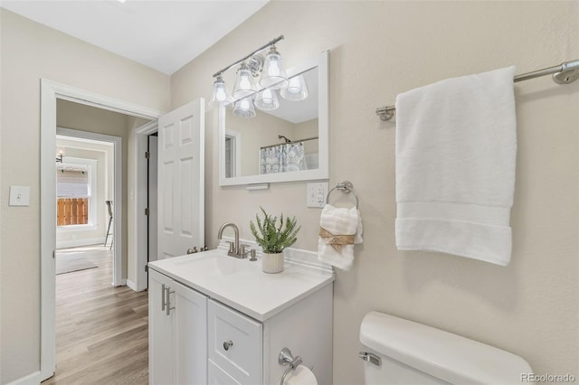 full bath with toilet, wood finished floors, and vanity