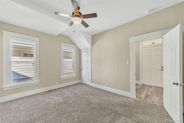 additional living space with visible vents, light carpet, a ceiling fan, baseboards, and vaulted ceiling