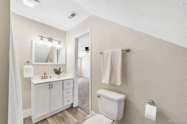 bathroom featuring vanity, wood finished floors, visible vents, lofted ceiling, and toilet