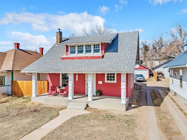 view of front of home featuring a porch, fence, roof with shingles, an outdoor structure, and a chimney