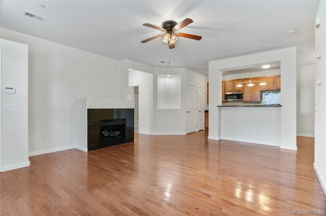 4100 Albion St Unit 614, Denver, CO 80216 - unfurnished living room with a ceiling fan, light wood-type flooring, a tile fireplace, and baseboards