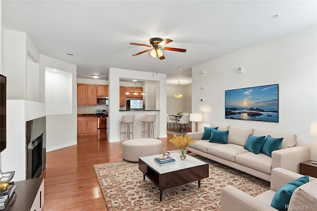 4100 Albion St Unit 614, Denver, CO 80216 - living area featuring a ceiling fan, light wood-style flooring, a fireplace, and baseboards