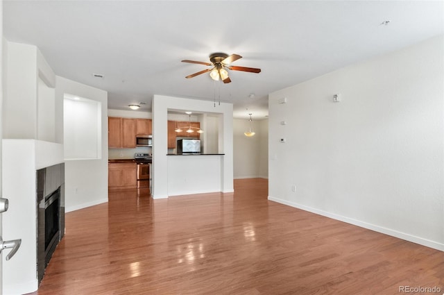 4100 Albion St Unit 614, Denver, CO 80216 - unfurnished living room with ceiling fan, light wood finished floors, a fireplace, and baseboards