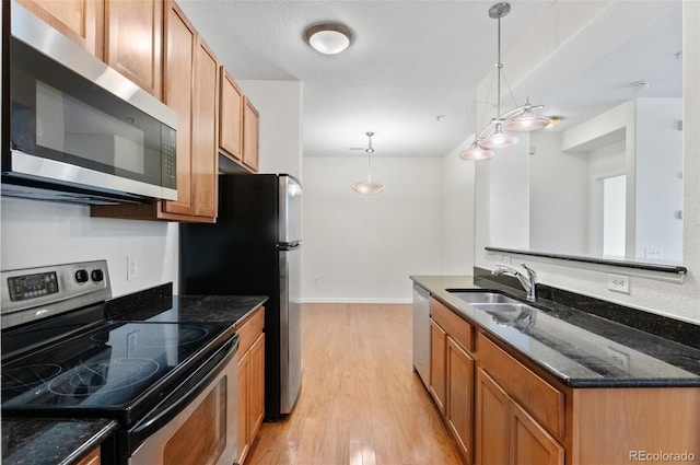 4100 Albion St Unit 614, Denver, CO 80216 - kitchen with stainless steel appliances, a sink, light wood-style flooring, and dark stone counters