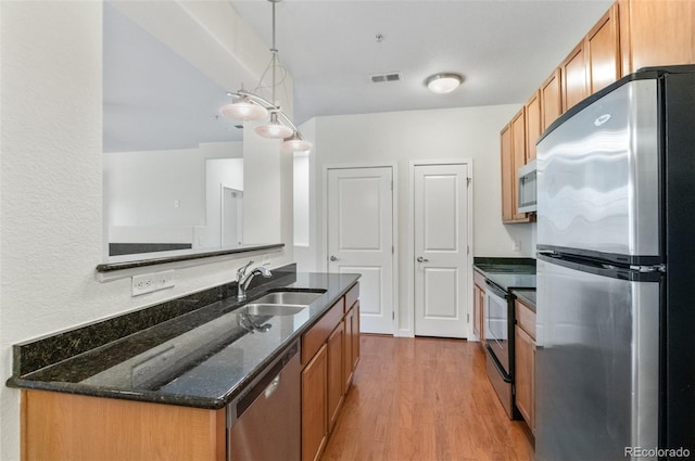 4100 Albion St Unit 614, Denver, CO 80216 - kitchen featuring stainless steel appliances, a sink, wood finished floors, dark stone countertops, and hanging light fixtures