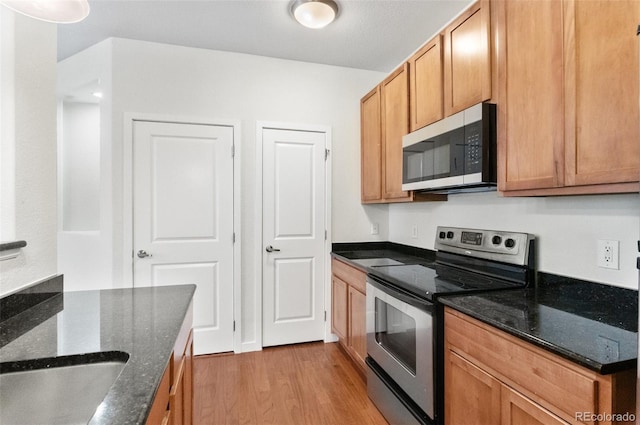 4100 Albion St Unit 614, Denver, CO 80216 - kitchen with appliances with stainless steel finishes, light wood-style floors, and dark stone countertops