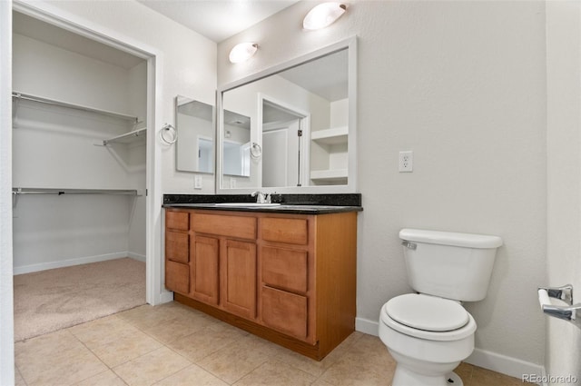 4100 Albion St Unit 614, Denver, CO 80216 - bathroom with vanity, a walk in closet, toilet, tile patterned flooring, and baseboards
