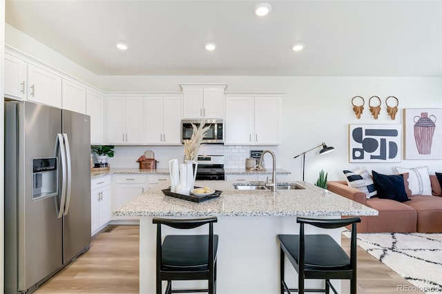 kitchen featuring sink, a kitchen island with sink, a kitchen breakfast bar, stainless steel appliances, and white cabinets