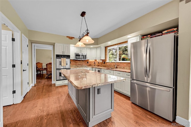 1583 Sunset Ridge Rd, Highlands Ranch, CO 80126 - kitchen featuring appliances with stainless steel finishes, a sink, light stone countertops, light wood finished floors, and white cabinets