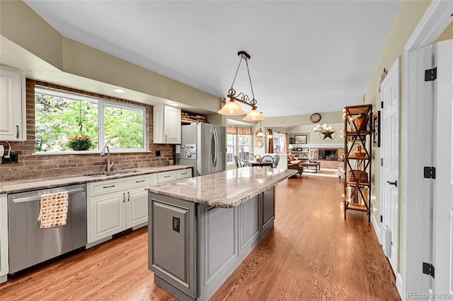 1583 Sunset Ridge Rd, Highlands Ranch, CO 80126 - kitchen featuring appliances with stainless steel finishes, a sink, open floor plan, decorative backsplash, and a kitchen island