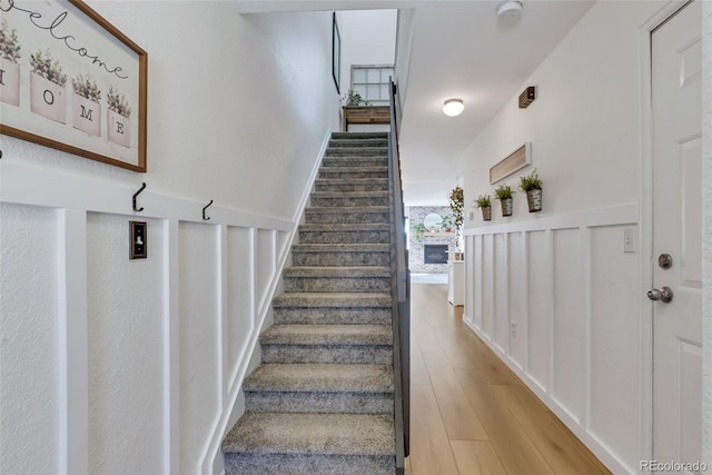 staircase featuring wood finished floors and wainscoting