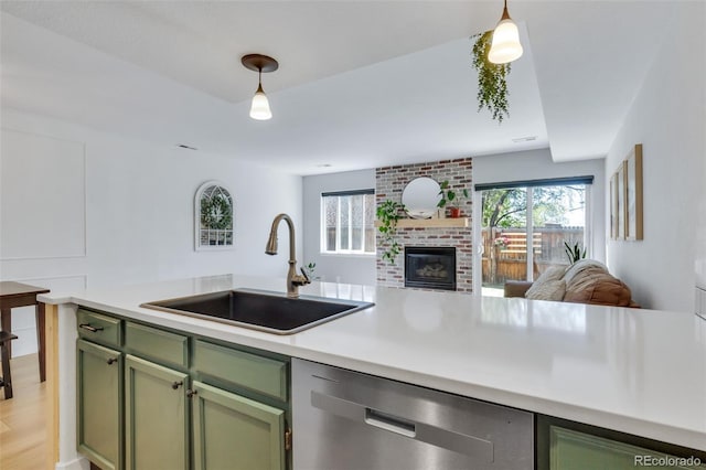 kitchen featuring green cabinetry, stainless steel dishwasher, a sink, open floor plan, and light countertops