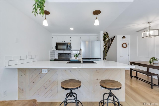 kitchen with black appliances, a sink, a peninsula, and a breakfast bar