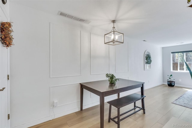 dining area featuring a chandelier, light wood-style floors, and baseboards