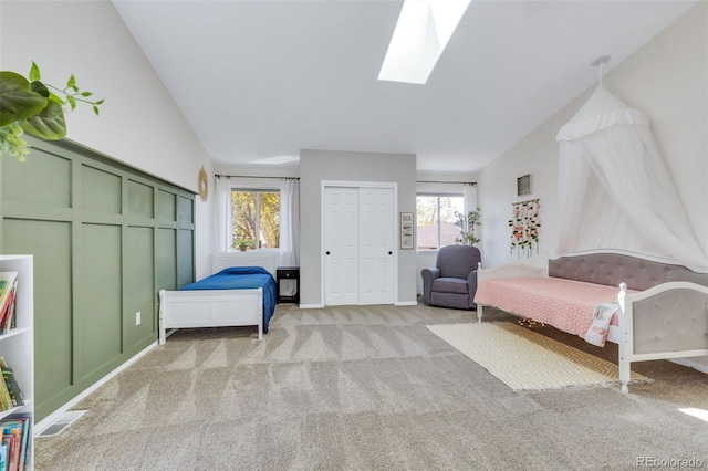 bedroom featuring light carpet, a skylight, and lofted ceiling
