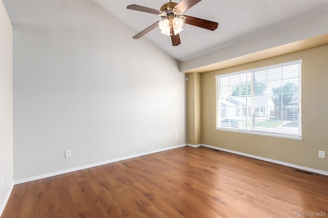 spare room featuring a textured ceiling, vaulted ceiling, wood finished floors, and visible vents