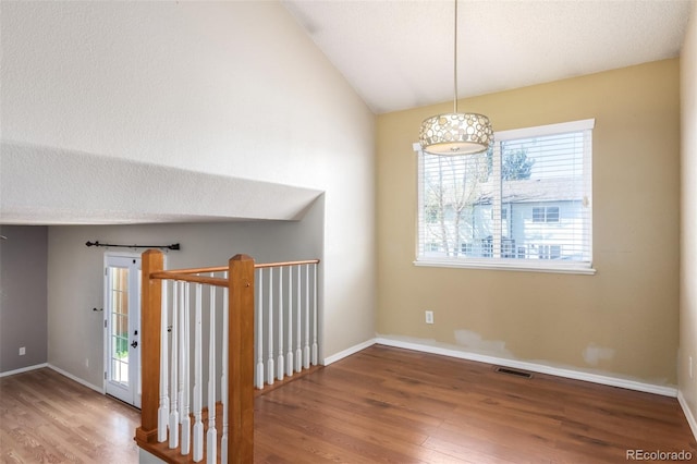 interior space with lofted ceiling, visible vents, baseboards, and wood finished floors