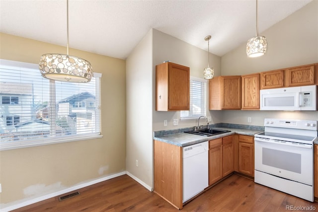 kitchen featuring white appliances, visible vents, lofted ceiling, wood finished floors, and a sink