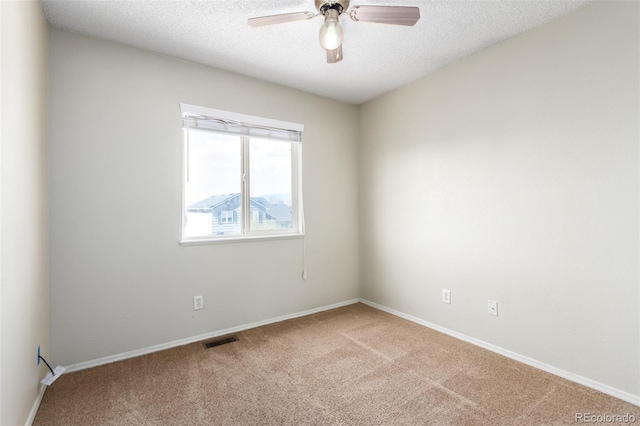 carpeted spare room with a textured ceiling, ceiling fan, visible vents, and baseboards