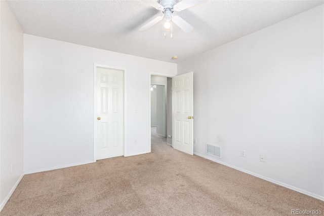 unfurnished bedroom featuring carpet, visible vents, a textured ceiling, and baseboards