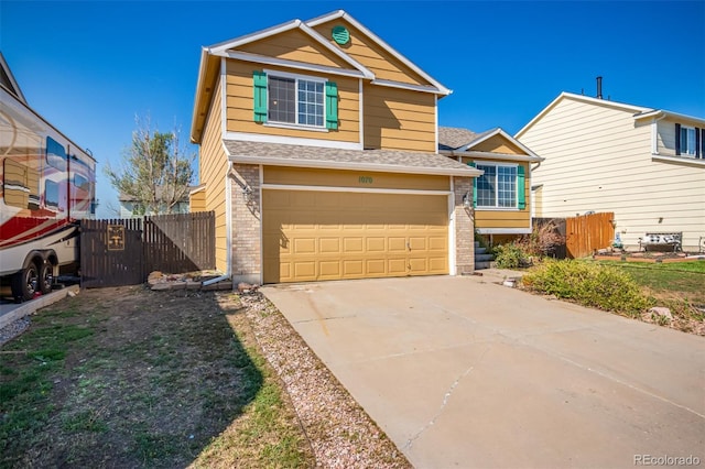 view of front of home with brick siding, driveway, an attached garage, and fence