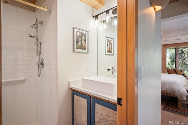 bathroom with a tile shower, vanity, and tile patterned floors