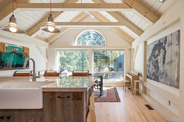 interior space with pendant lighting, sink, beam ceiling, light hardwood / wood-style flooring, and high vaulted ceiling