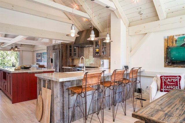 kitchen with lofted ceiling with beams, pendant lighting, light hardwood / wood-style floors, a center island, and high end refrigerator