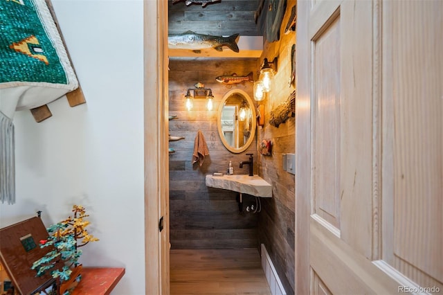 bathroom featuring wood-type flooring, wooden walls, and sink