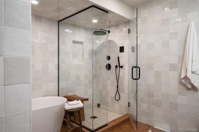 bathroom with shower with separate bathtub, tile walls, and tile patterned flooring