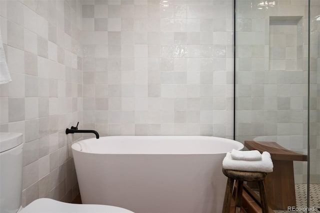 bathroom with a bathtub, tile walls, and toilet