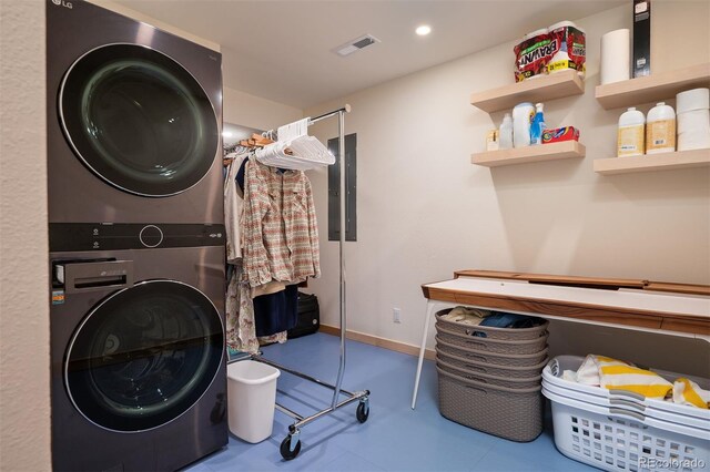 laundry area with electric panel and stacked washer / drying machine