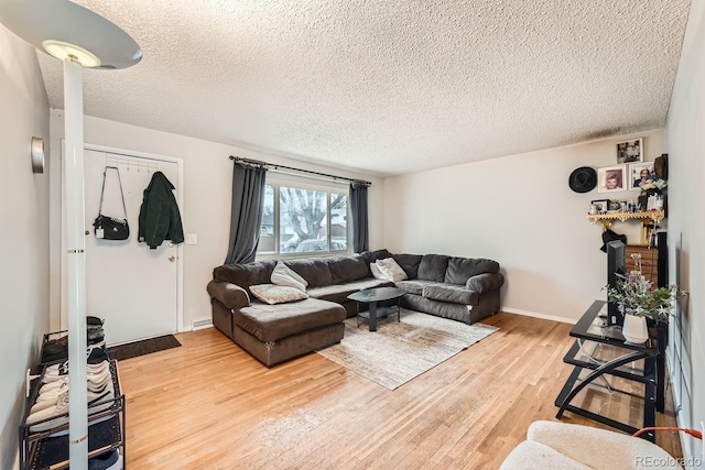 living area featuring a textured ceiling, baseboards, and wood finished floors