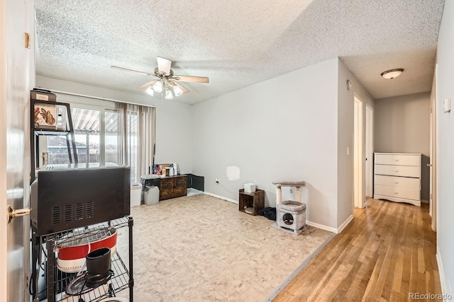 rec room featuring ceiling fan, a textured ceiling, and baseboards