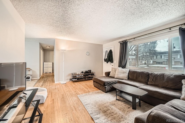 living room featuring a textured ceiling, wood finished floors, and baseboards