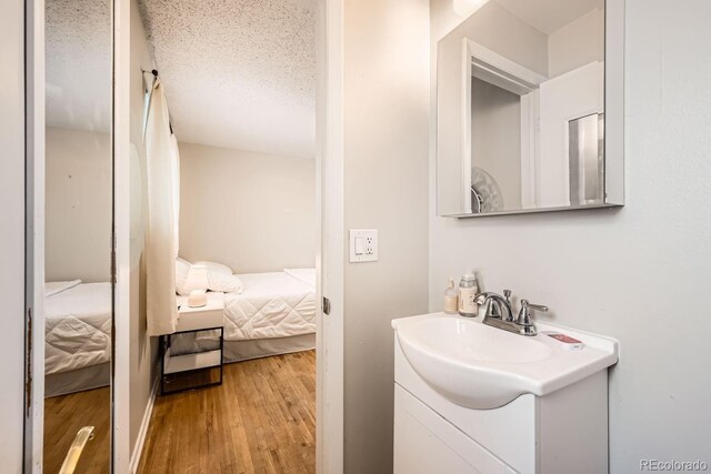 bathroom with a textured ceiling, wood finished floors, connected bathroom, and vanity